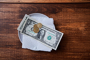 Change and cash tip left on plate on wooden table
