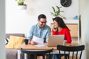 Couple at table with paperwork and computer