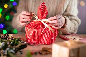Person wrapping small red present with bow