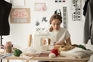 Female tailor stitching on sewing machine in design studio